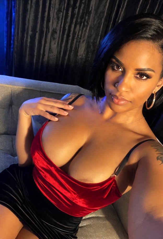 roxxy is trailing a finger down the viewer's chest,black silk slip dress,gold hoop earrings,red satin blouse,black bo…