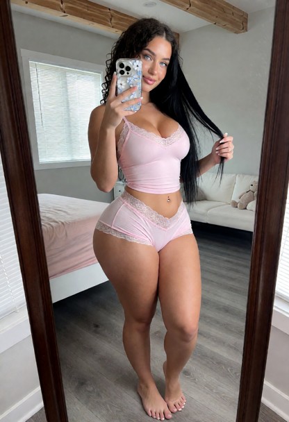 A full-length vertical mirror selfie of a young adult woman with long, straight black hair styled with a center part.…