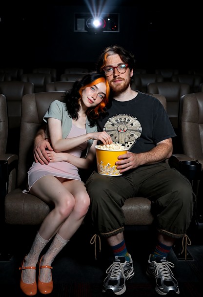 A semi-realistic cinematic movie-theater scene featuring **Ha-yul**, a 26-year-old Korean woman, sitting on the **lef…