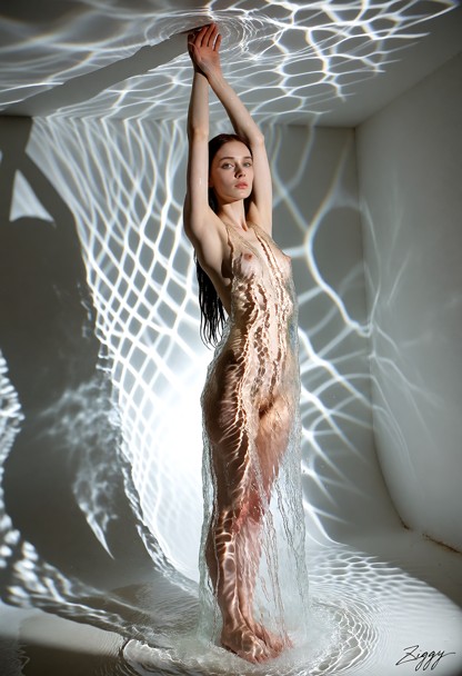 A gown made entirely of clear running water, photographed as a fashion campaign picture in a bare white room. One har…