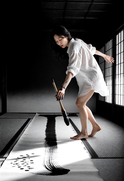 Black and white photograph. Everything in the frame is black, white or grey — grey tatami, white paper, white paper s…