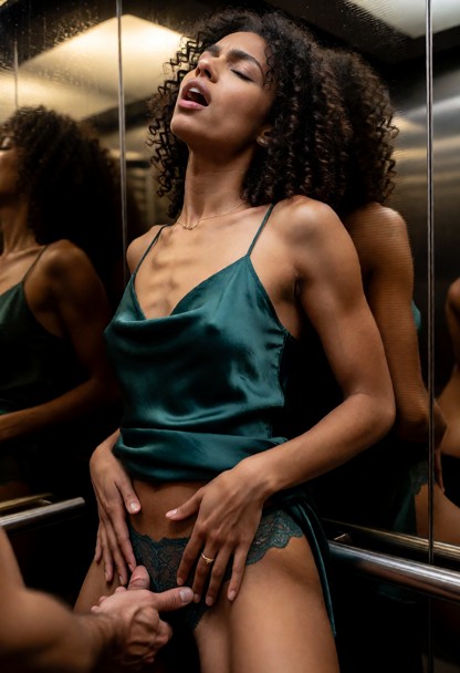 Location: dimly lit hotel elevator with polished mirrored walls that reflect the soft, warm overhead light, creating …