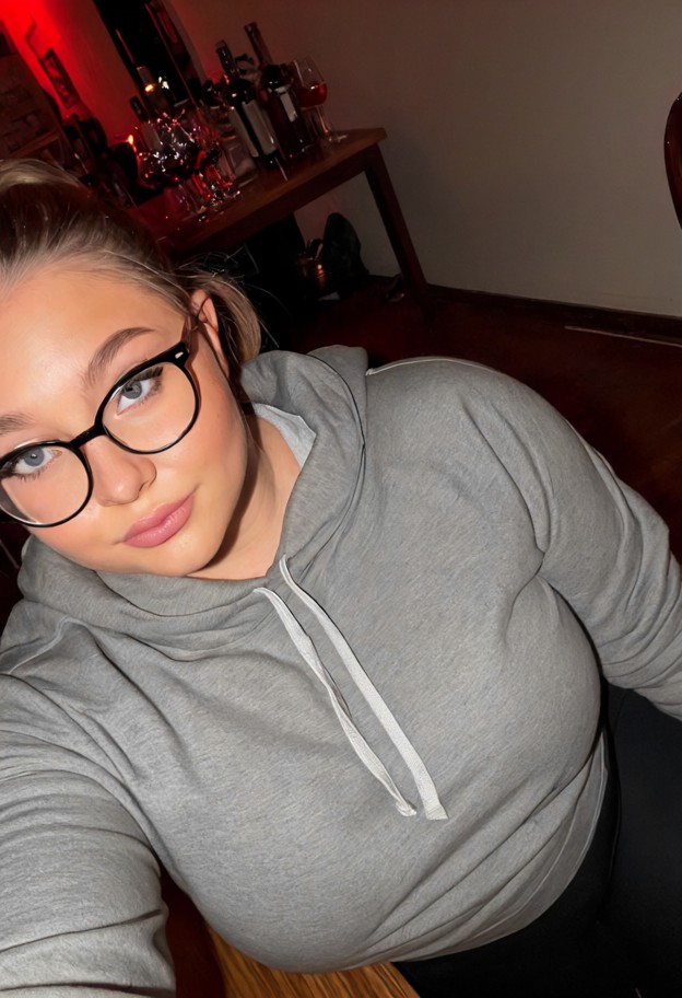 madison is pulling her hoodie tight,oversized gray cotton hoodie,black leggings,dim indoor lounge,drinks table,medium…