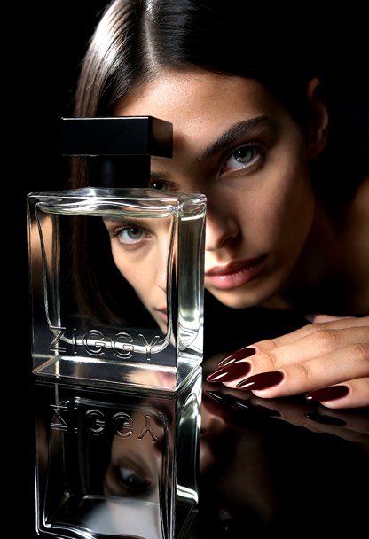 A luxury fragrance campaign photograph, black studio, one hard light and nothing else lit. Macro, very close: a heavy…