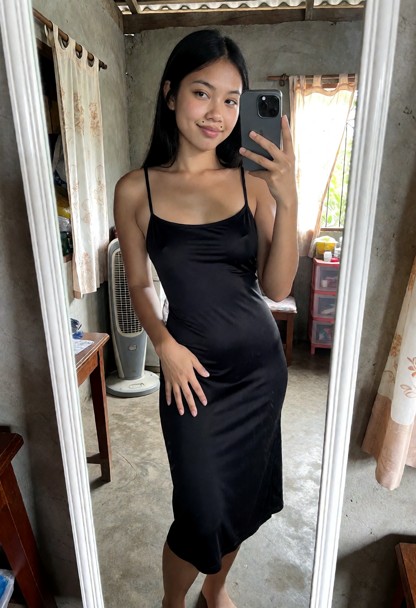 She records herself in the full-length mirror with her phone, wearing the same fitted black spaghetti-strap dress.
S…